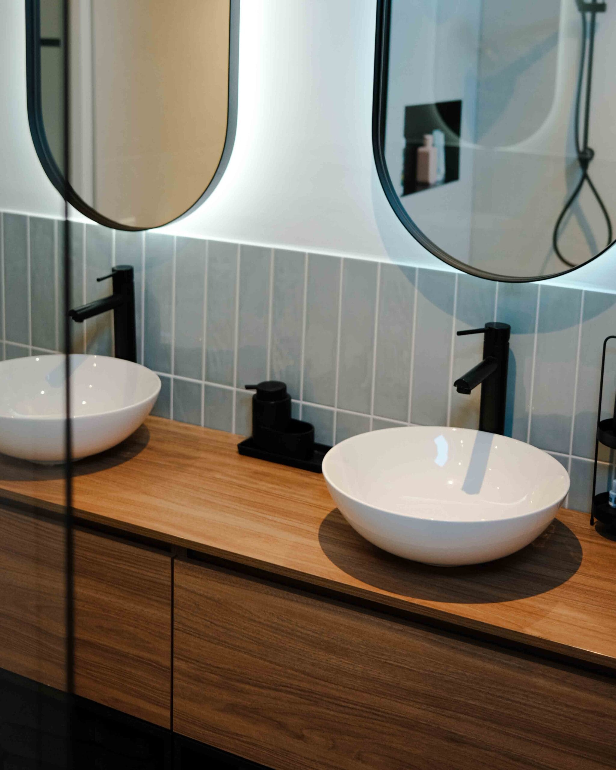 Gerealiseerde badkamer met houten wastafelmeubel en ronde spiegels
